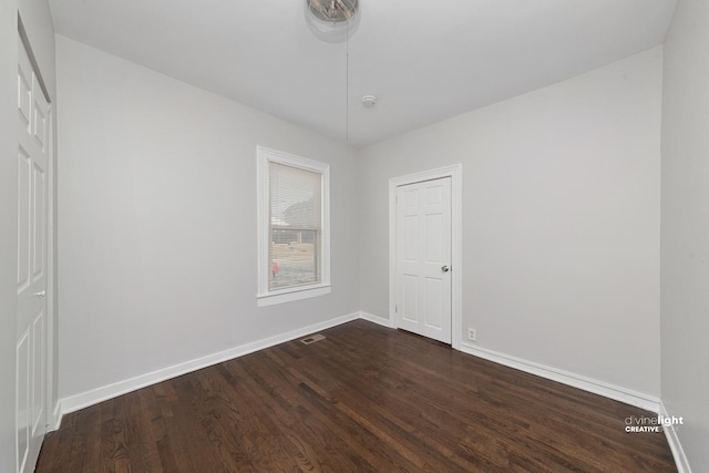 unfurnished bedroom with dark wood-style floors, visible vents, and baseboards