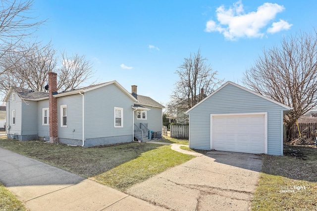 view of side of property featuring a detached garage, an outbuilding, fence, and driveway