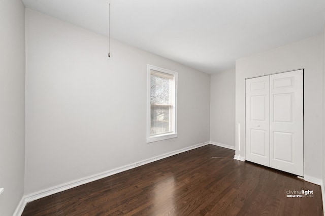 unfurnished bedroom featuring a closet, baseboards, and dark wood-style flooring