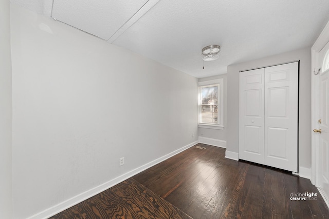 unfurnished bedroom featuring dark wood-style floors, baseboards, and a closet