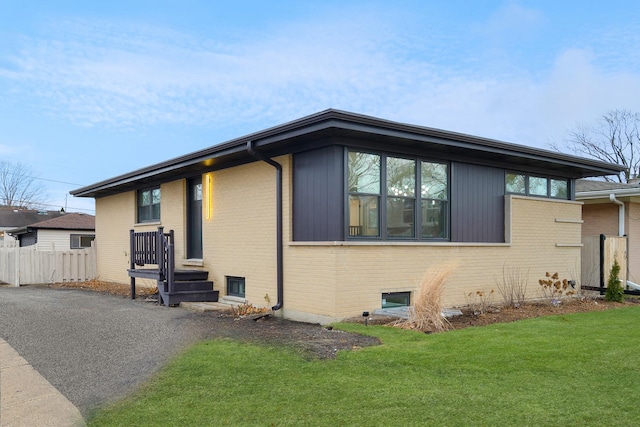 view of front facade featuring brick siding, a front lawn, and fence