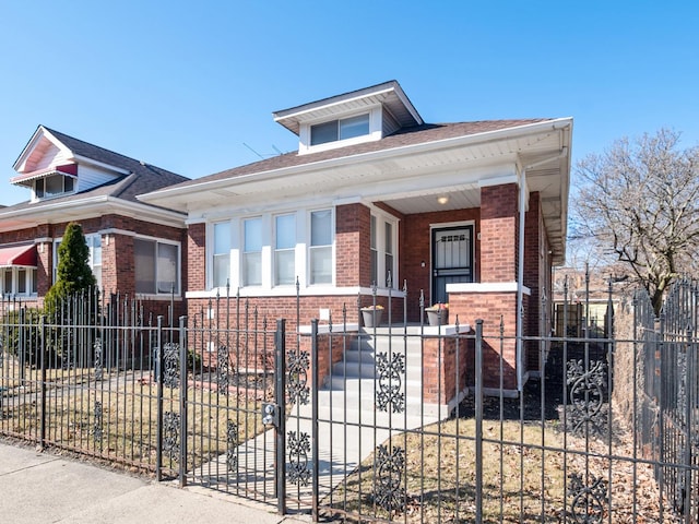 bungalow featuring brick siding, a porch, and a fenced front yard