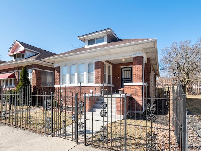 bungalow-style house with covered porch, brick siding, and a fenced front yard