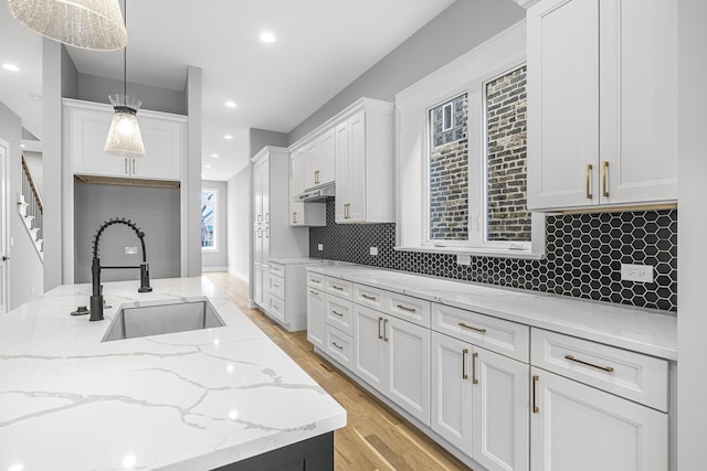3308 S Leavitt St, Chicago, IL 60608 - kitchen with light stone countertops, white cabinetry, a sink, light wood-type flooring, and pendant lighting