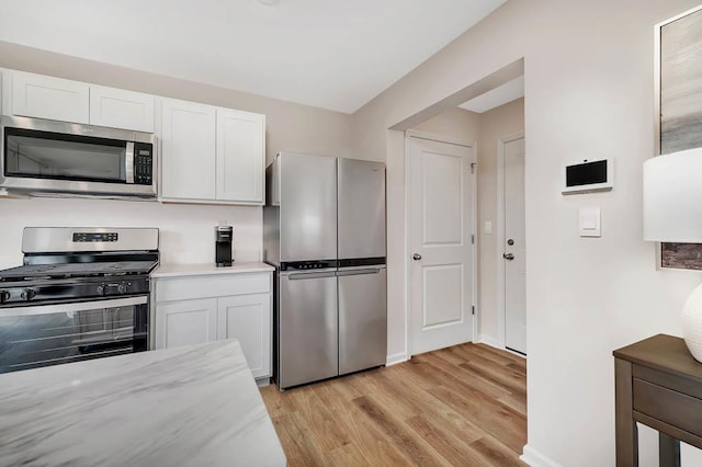 kitchen with light wood finished floors, white cabinetry, stainless steel appliances, and baseboards