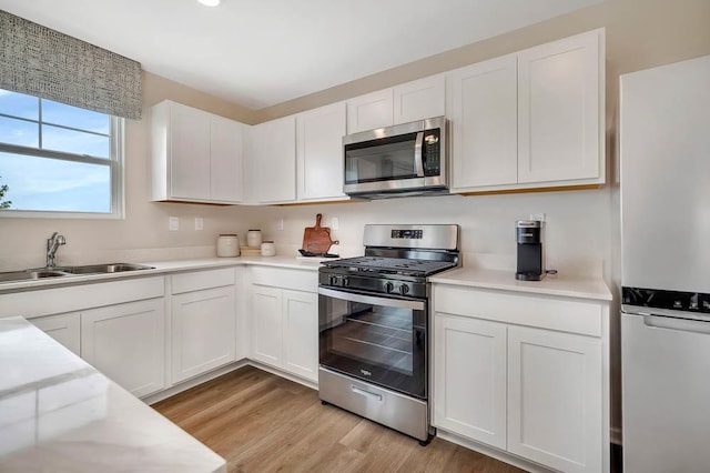 kitchen with a sink, light countertops, white cabinets, and stainless steel appliances