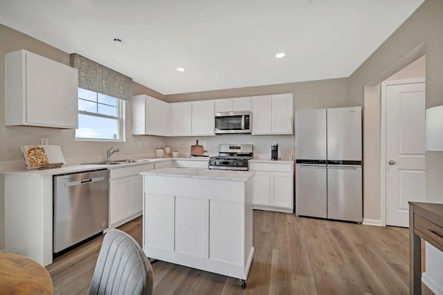 kitchen featuring light wood-style flooring, white cabinets, stainless steel appliances, and light countertops