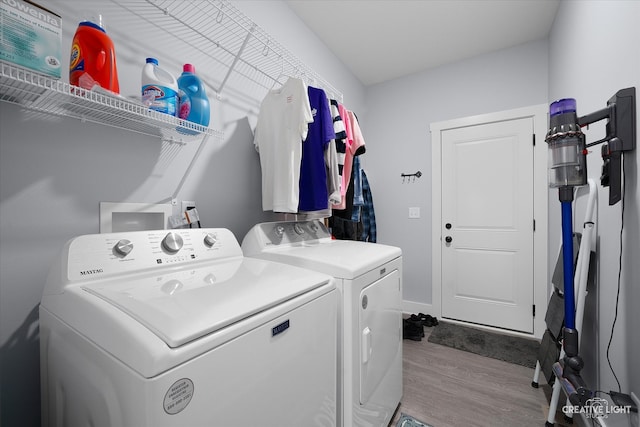 clothes washing area with laundry area, washer and dryer, and wood finished floors