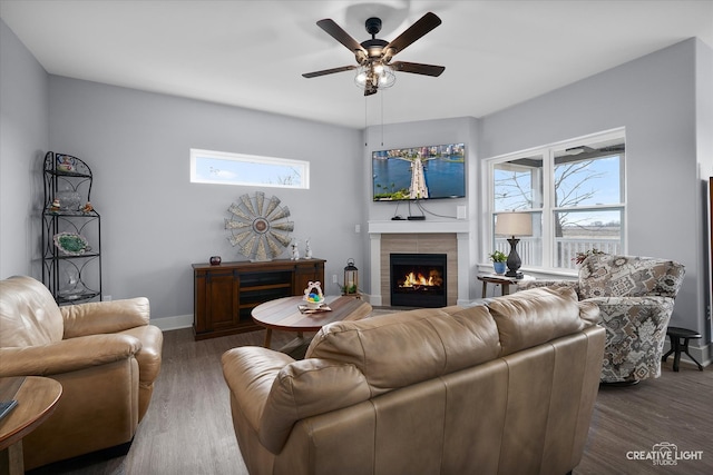 living room featuring a fireplace, baseboards, ceiling fan, and wood finished floors