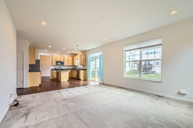 unfurnished living room featuring visible vents, baseboards, recessed lighting, dark colored carpet, and a sink