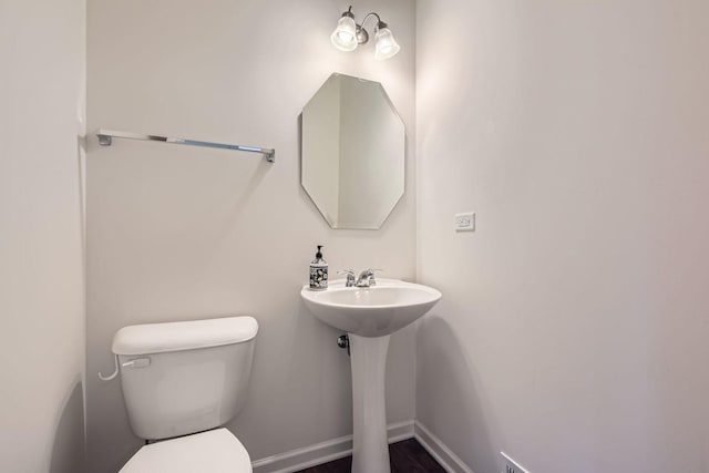 bathroom featuring toilet, baseboards, and a sink