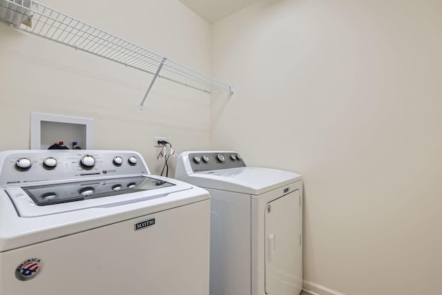 washroom featuring laundry area, washing machine and dryer, and baseboards