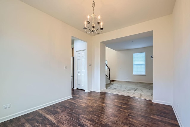 unfurnished room with a notable chandelier, stairway, baseboards, and wood finished floors