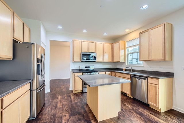 kitchen with dark countertops, light brown cabinets, appliances with stainless steel finishes, and a sink