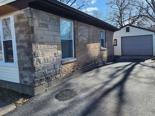 view of home's exterior with brick siding, driveway, an outbuilding, and a garage