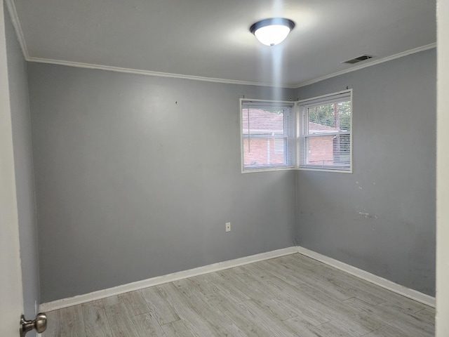 spare room with baseboards, wood finished floors, visible vents, and ornamental molding