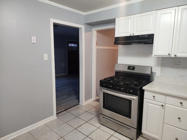 kitchen featuring light tile patterned flooring, white cabinets, under cabinet range hood, stainless steel gas range oven, and crown molding