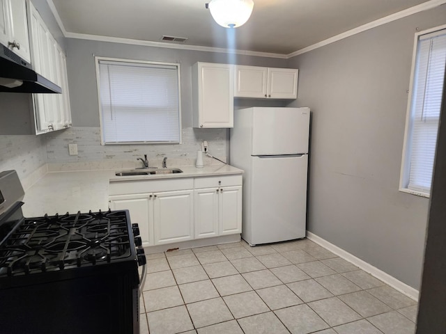 kitchen with visible vents, freestanding refrigerator, ornamental molding, a sink, and gas range