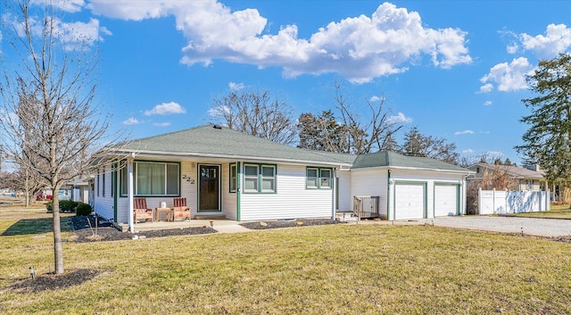 view of front facade with a front yard, fence, driveway, covered porch, and a garage