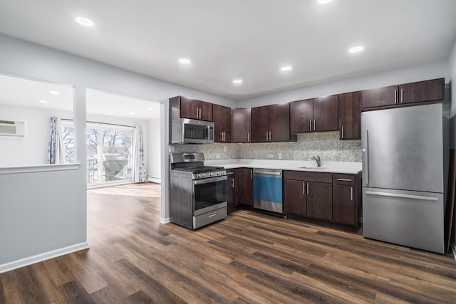 kitchen with dark brown cabinets, dark wood finished floors, light countertops, stainless steel appliances, and a sink