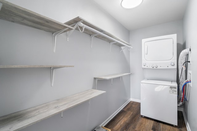 clothes washing area with baseboards, dark wood-type flooring, laundry area, and stacked washing maching and dryer