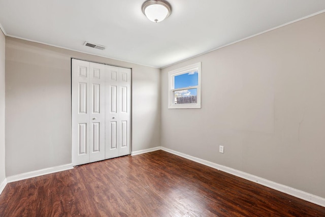 unfurnished bedroom with a closet, visible vents, baseboards, and wood finished floors