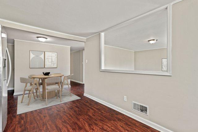 unfurnished dining area with ornamental molding, wood finished floors, visible vents, and baseboards