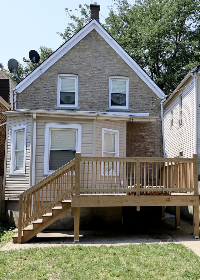 back of house featuring a chimney, brick siding, and a wooden deck