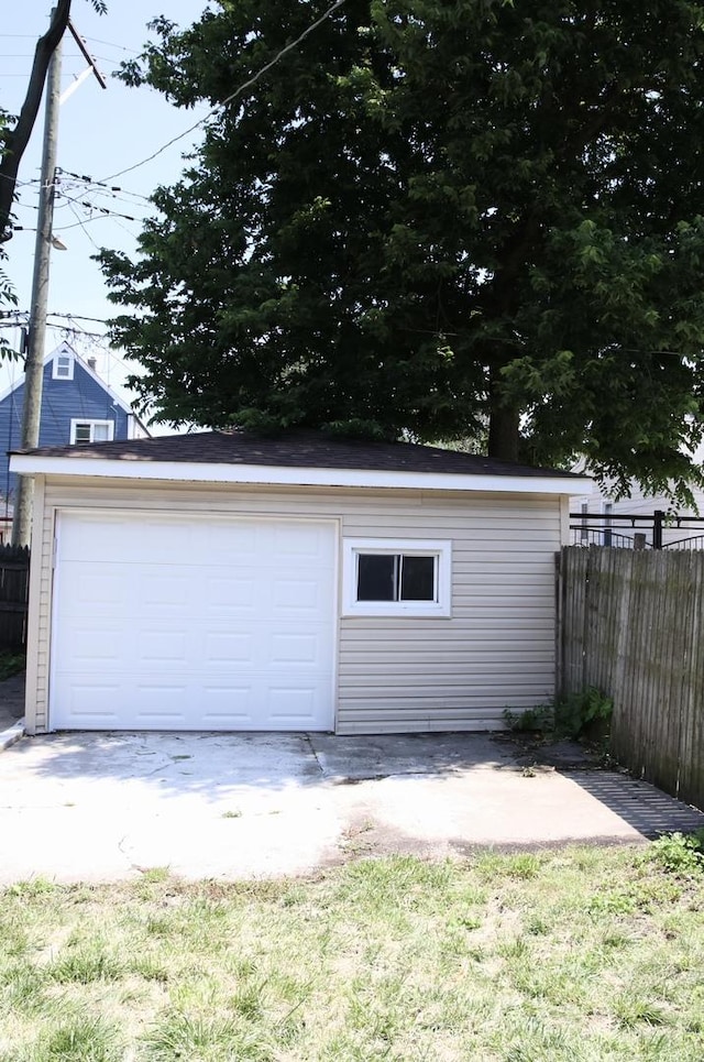 detached garage with concrete driveway and fence