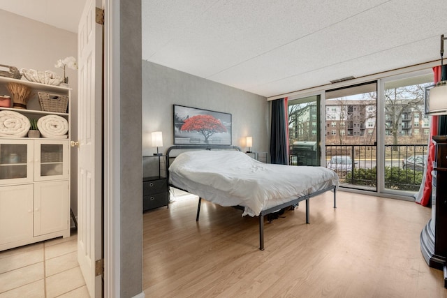 bedroom featuring access to outside, wood finished floors, and expansive windows