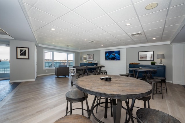 dining area with a drop ceiling, light wood-type flooring, baseboards, and visible vents