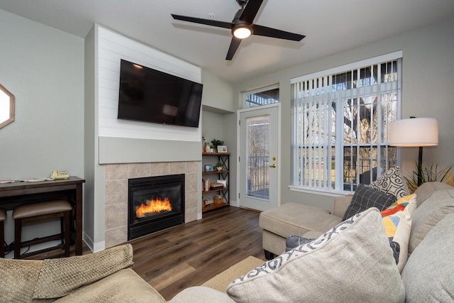 living room with baseboards, wood finished floors, a ceiling fan, and a tile fireplace