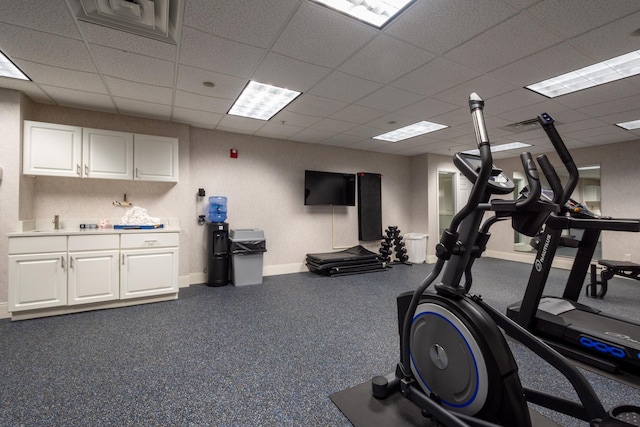 exercise room featuring a drop ceiling and baseboards