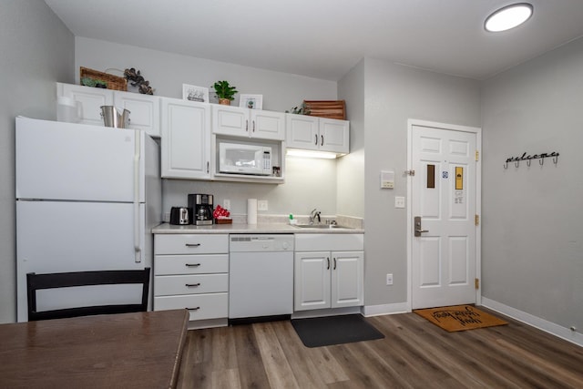 kitchen with a sink, dark wood finished floors, white cabinetry, white appliances, and light countertops