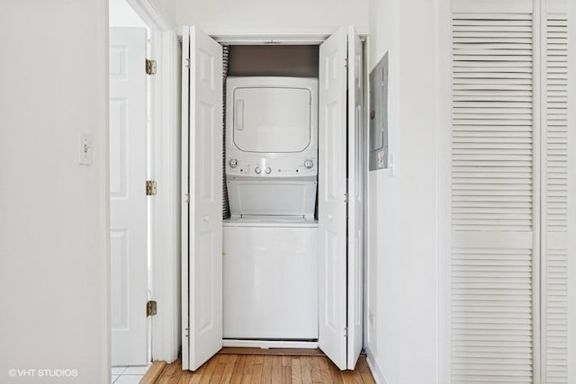 laundry area featuring stacked washer and clothes dryer, light wood-style flooring, and laundry area