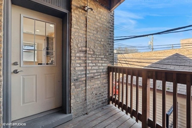 view of exterior entry with a balcony and a shingled roof