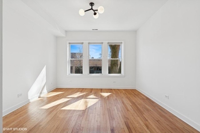 empty room featuring baseboards and light wood finished floors