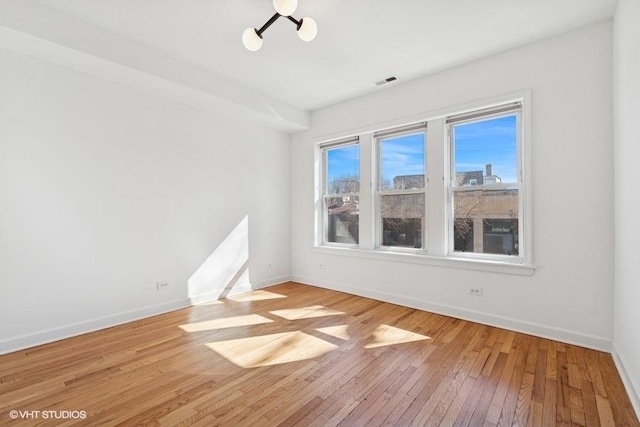 spare room with visible vents, baseboards, and wood-type flooring