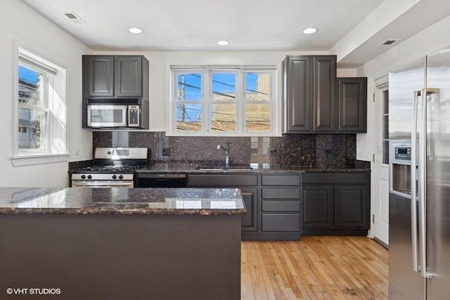 kitchen featuring a sink, dark stone counters, visible vents, and stainless steel appliances