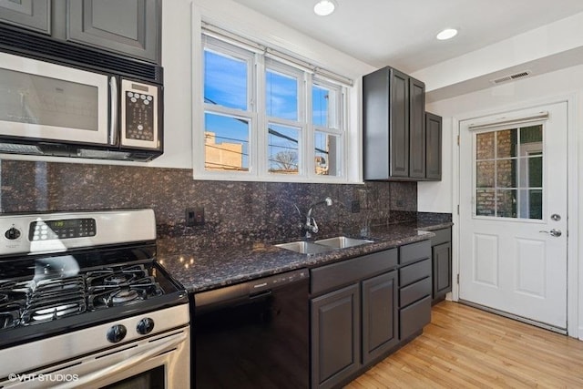 kitchen with visible vents, a sink, black dishwasher, decorative backsplash, and gas range