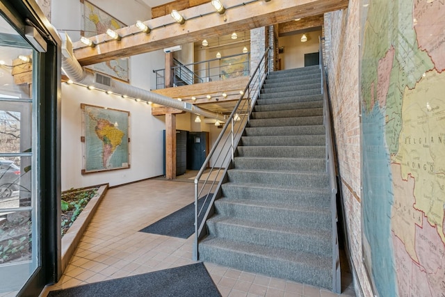 staircase with tile patterned flooring, visible vents, and a towering ceiling