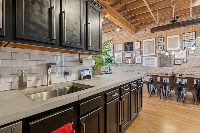 kitchen with light wood finished floors, brick wall, wood ceiling, beam ceiling, and a sink