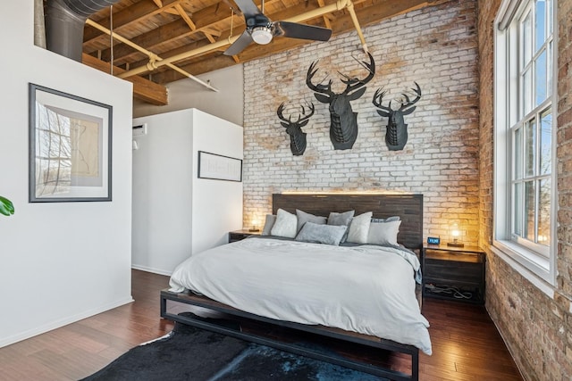 bedroom featuring wood finished floors, baseboards, brick wall, wooden ceiling, and beamed ceiling