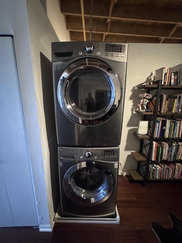 clothes washing area featuring laundry area, wood finished floors, and stacked washer and dryer