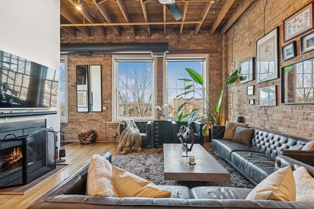 living room featuring a high ceiling, wood finished floors, brick wall, and ceiling fan