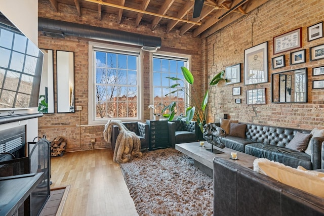 living area featuring a towering ceiling, wood finished floors, and brick wall