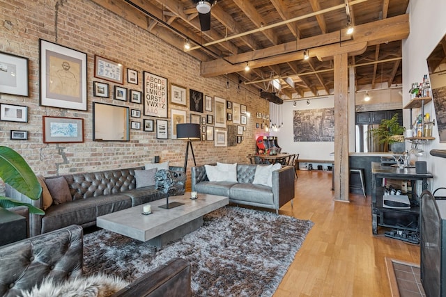 living room featuring brick wall, wood ceiling, rail lighting, and wood finished floors