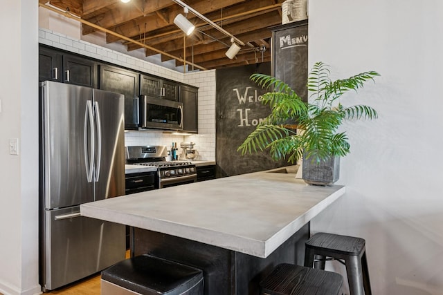 kitchen featuring a breakfast bar, backsplash, stainless steel appliances, a peninsula, and light countertops