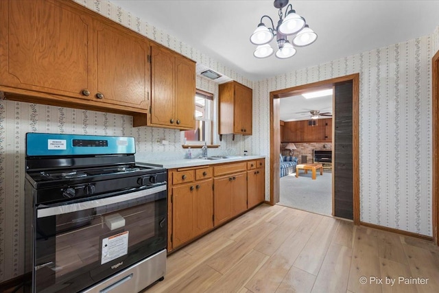 kitchen featuring visible vents, wallpapered walls, a sink, stainless steel range, and light countertops