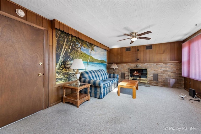 living room with visible vents, wood walls, carpet flooring, and ceiling fan